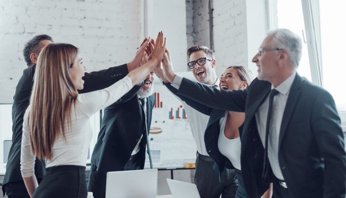 cheerful-business-team-giving-each-other-high-five-to-success-while-working-in-the-modern-office